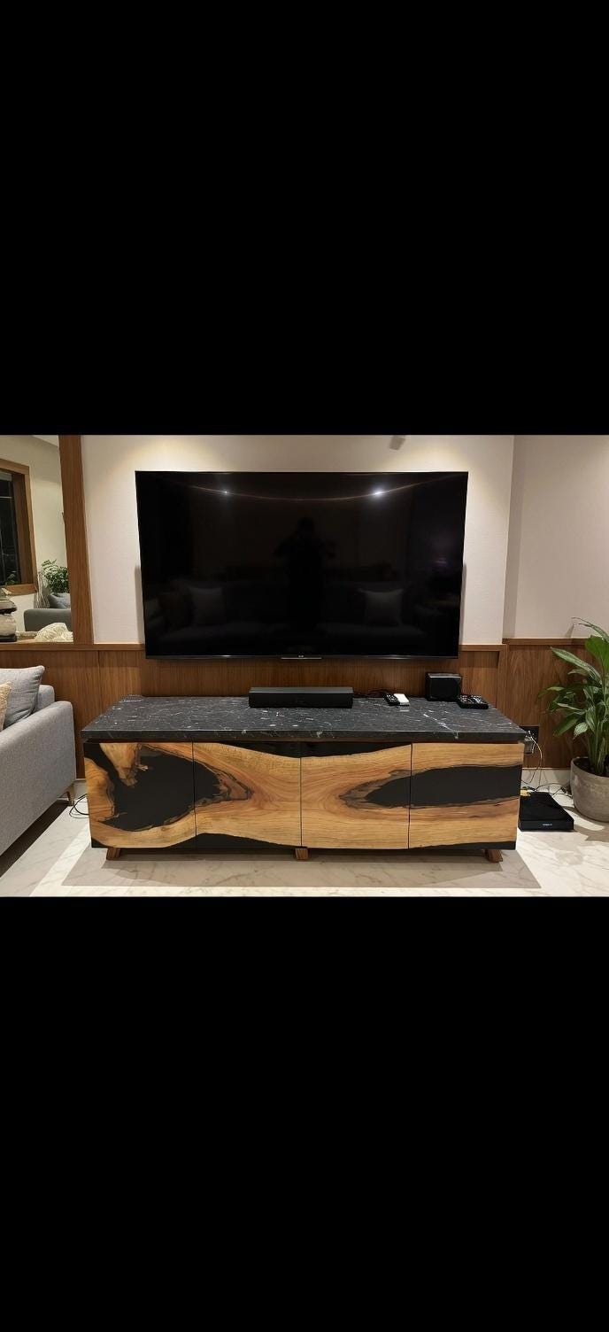 Modern living room with a large flat-screen TV on a wooden stand.