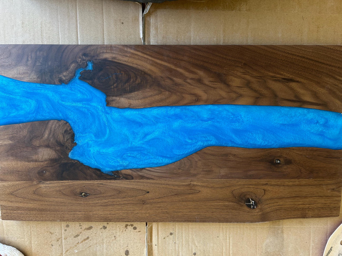 Wooden surface with blue resin flow design on a wooden background