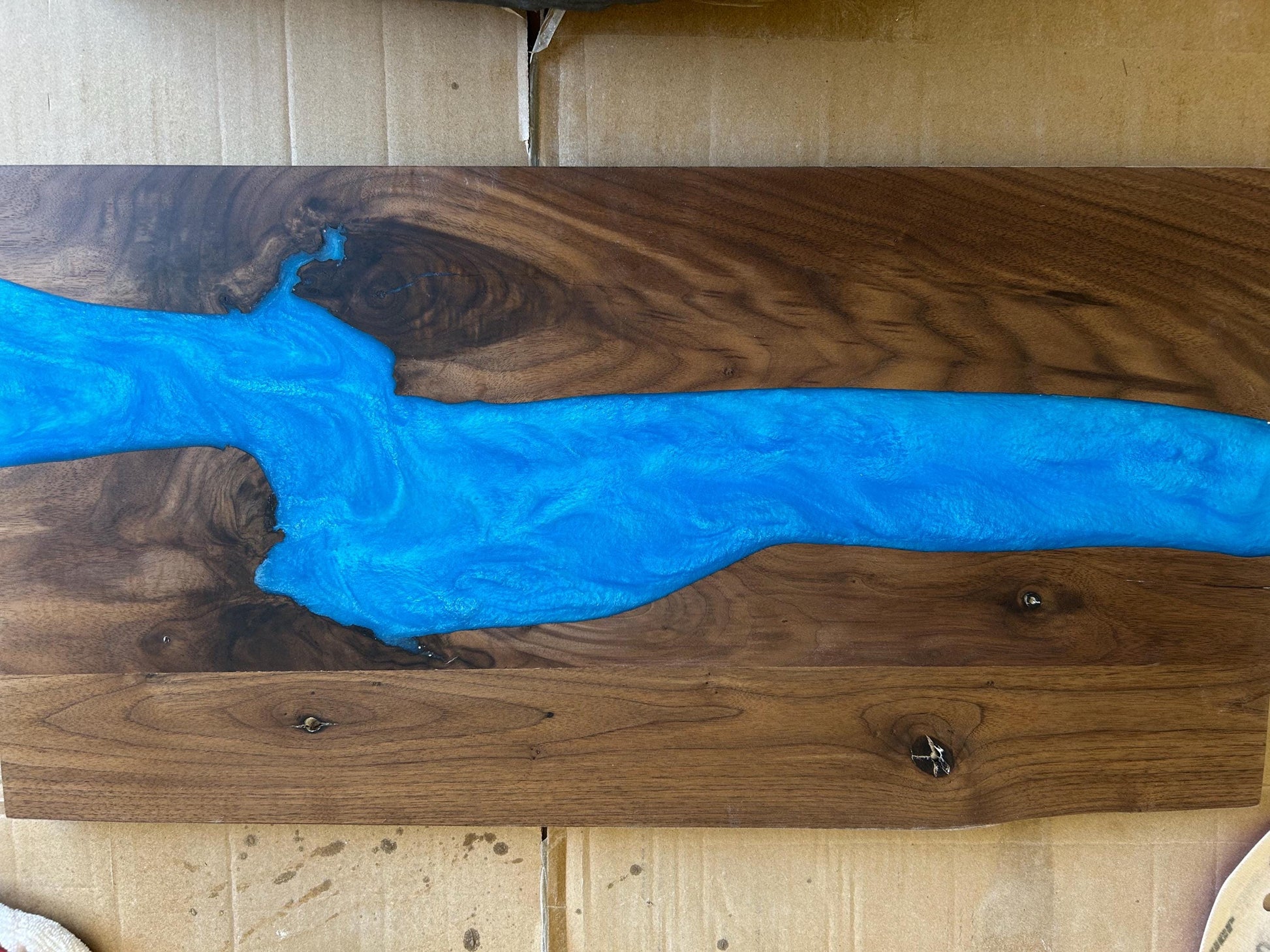 Wooden surface with blue resin flow design on a wooden background