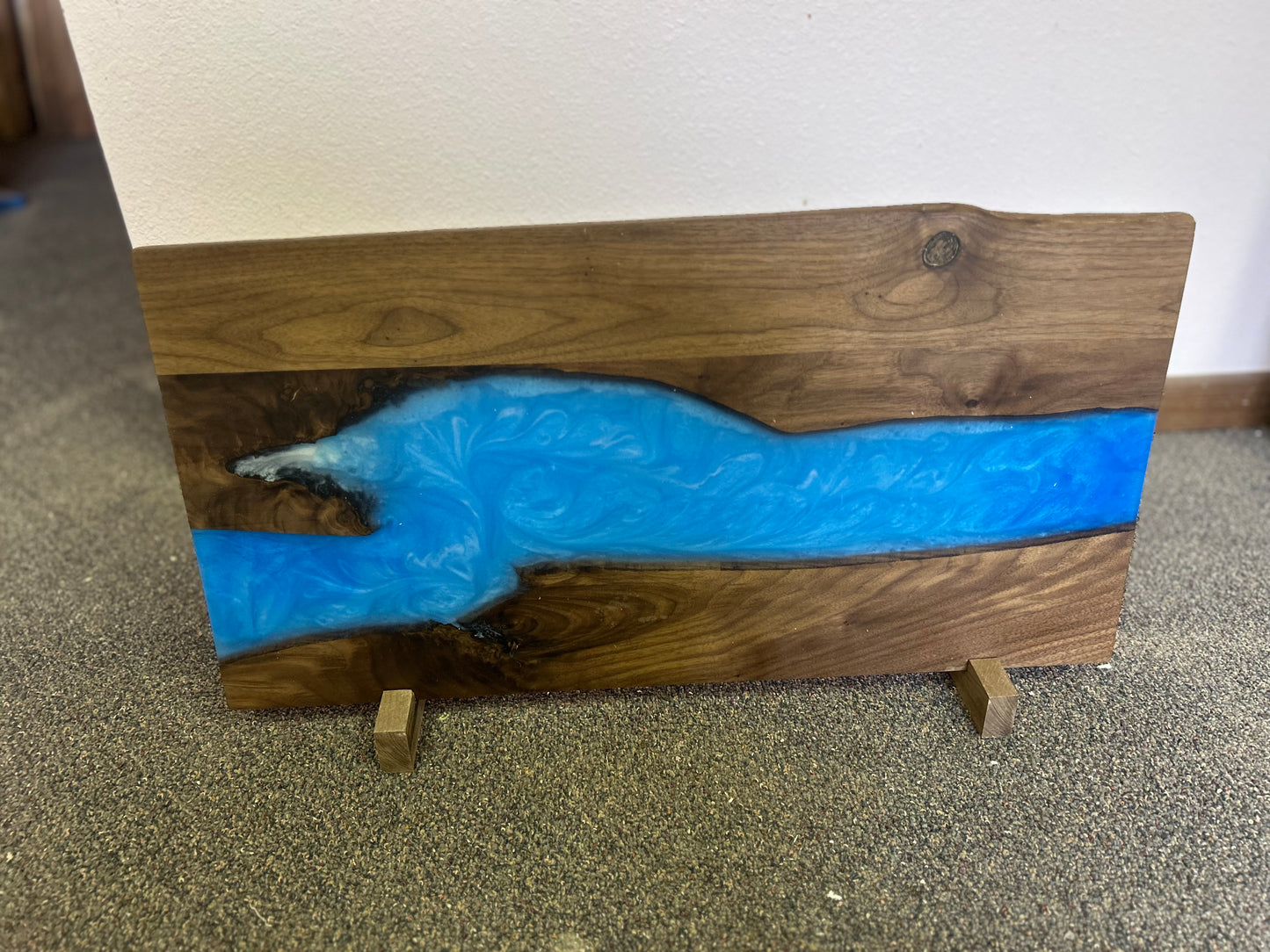 Wooden board with blue resin inlay on a carpeted floor