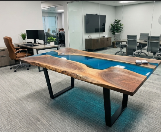 A large live-edge wood conference table with a glossy blue resin river running through the center, supported by black metal legs, shown in a modern office setting.