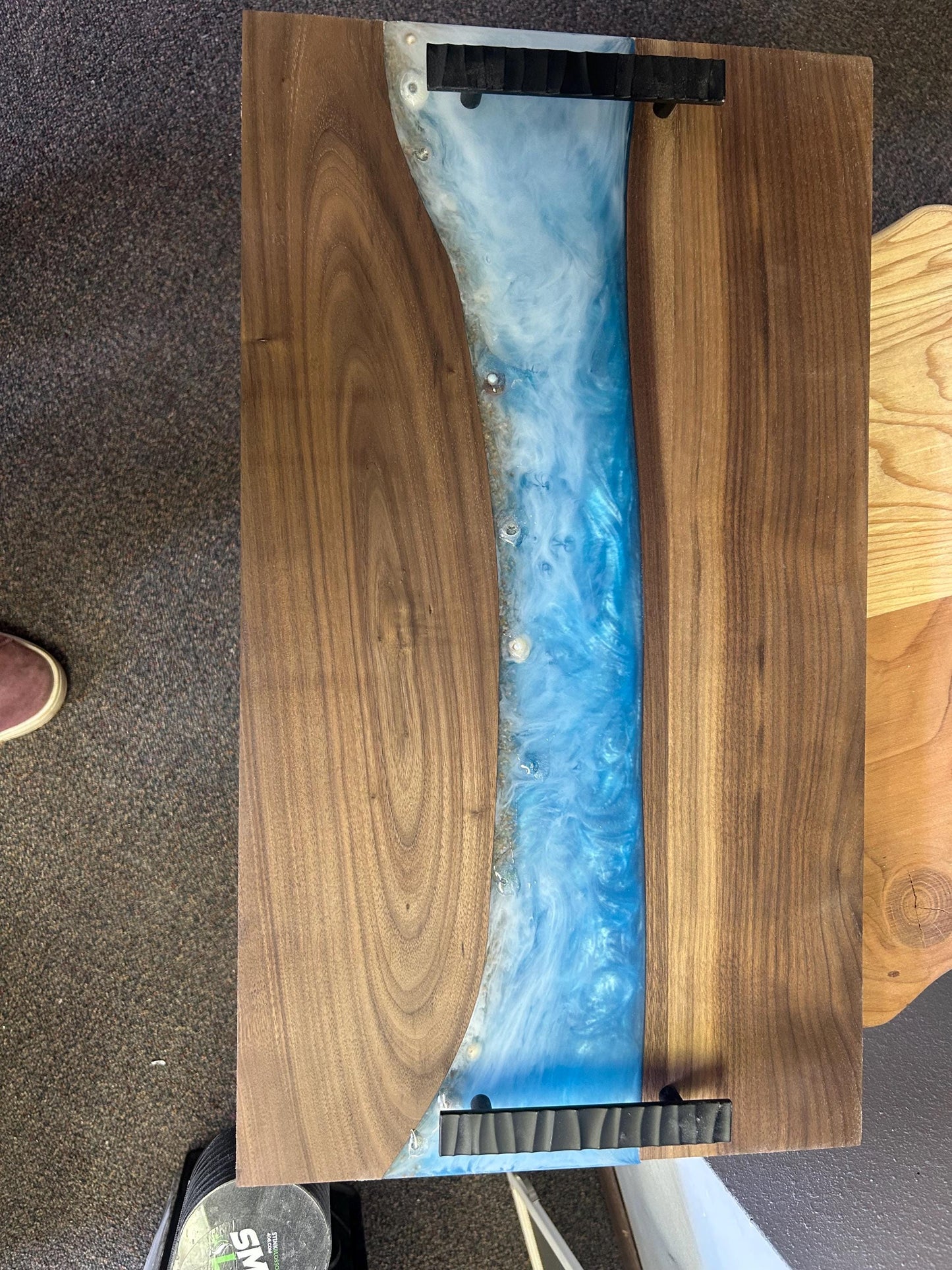Wooden table with a blue resin inlay on a carpeted floor